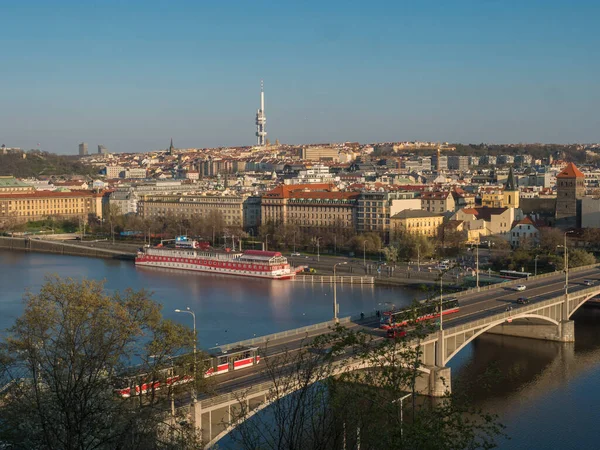 Prag Eski ve Yeni Şehir mimari çatısının manzarası ve Vltava Nehri üzerindeki Manes Köprüsü Letna Hill Parkı 'ndan görülen yüzen ev ve tramvay, güneşli bahar günü, mavi gökyüzü, Çek Cumhuriyeti — Stok fotoğraf