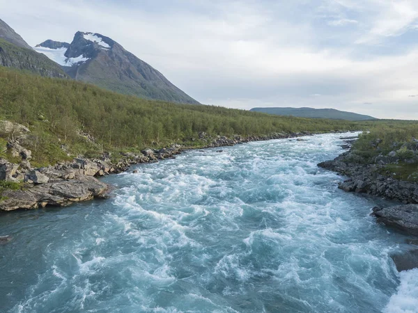 Vuojatadno Nehri 'nin mavi suları Akka Dağı, Ahkka Tepesi' nin karlı, buzullu ve huş ağacı ormanlarıyla doludur. İsveç Laponya 'sında güzel bir kuzey kutup manzarası. Yaz akşamı. — Stok fotoğraf