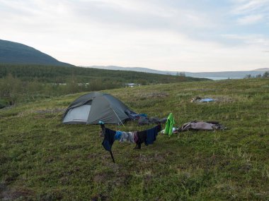 Yeşil çadır, asılı giysiler, güzel doğa, Akka dağ kitlesi, kar, buzullar, Vuojatadno nehri ve İsveç Laponya topraklarında huş ağacı Padjelantaleden yürüyüş patikası..