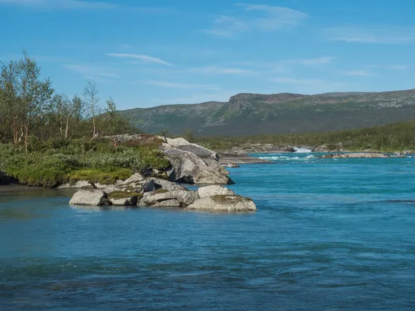 Kilátás türkiz kék víz vad Vuojatadno folyó. Északi táj svéd Lappföld nyírfa erdő és zöld hegyek Padjelantaleden túraútvonal. Nyári napsütéses nap, kék ég — Stock Fotó