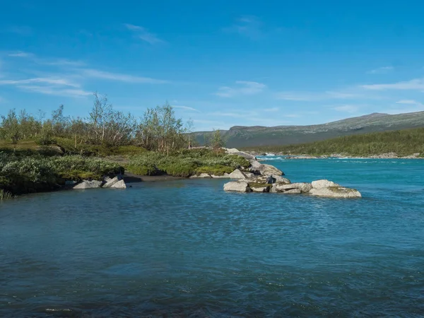 野生のBuojatadno川のターコイズブルーの水の眺め。スウェーデンの北部の風景白樺の木の森とPadjelantaledenハイキングコースで緑の山々とラップランド。夏の晴れた日青い空 — ストック写真