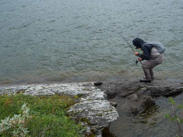 湖の海岸フライフィッシングで男漁師釣り人とキャッチマスやチャーフィッシュでGieddavrreスウェーデンの湖Padjelantaledenハイキングトレイルのラップランド. — ストック写真