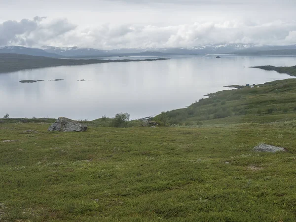 Lapland paisagem no lago Virihaure com sami aldeia Arasluokta casas, montanhas cobertas de neve e planície com arbustos. Suécia verão moody e nevoeiro natureza selvagem, Padjelantaleden trilha caminhadas. — Fotografia de Stock