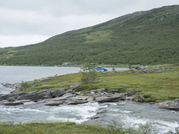 Staloluokta, Norrbotten, Svédország, Agust 11, 2021: Két Fiskeflyg helikopter turistákkal és felszereléssel Staloluokta faluban, Virihaure tónál, nyári ködös napon. Padjelanta Lappföld — Stock Fotó