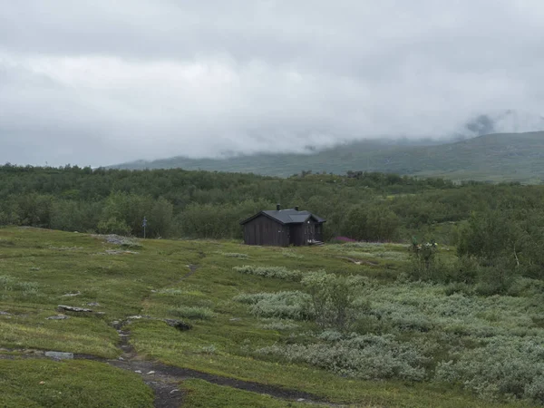 사미 마을 비리하레 호수에 있는 스콜 루 오츠 타 (Staloluokta) 는 집 과 별장, 산 과 자작나무가 있다. 파델 란 탈 레딘 하이킹 코스에서 여름 날씨가 온화하고 안개낀 날이다. 스웨덴 라플란드 의경 치 — 스톡 사진