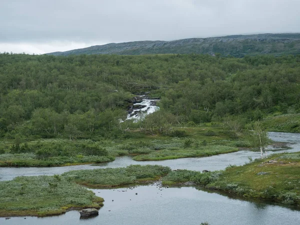 Lappföldi táj folyóval, kis vízeséssel, zöld hegyekkel, nyírfa erdőkkel. Svédország nyári hangulatos és ködös vad természet, Padjelantaleden túraútvonal. — Stock Fotó