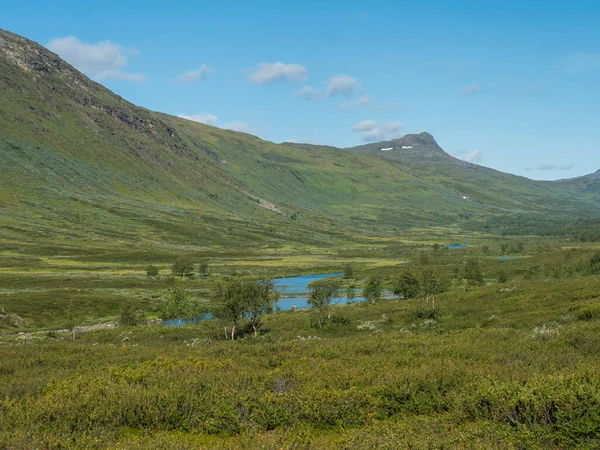 Schöne nördliche Landschaft, Tundra in Schwedisch Lappland mit blauem Fluss und See, grünen Hügeln und Bergen am Padjelantaleden-Wanderweg. Sommertag, blauer Himmel, weiße Wolken — Stockfoto