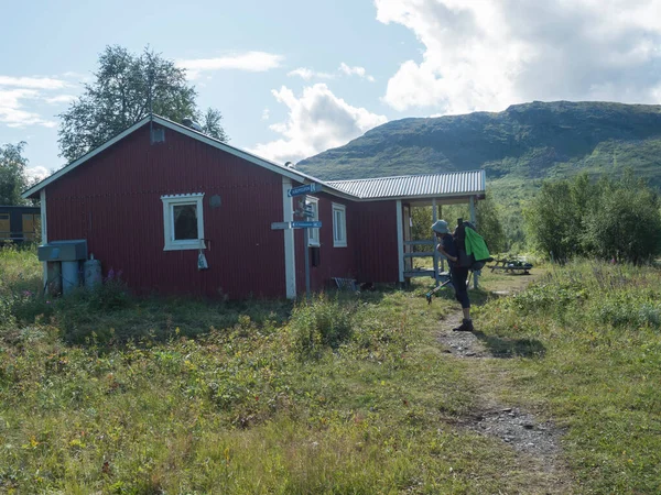 Padjelanta, Norrbotten, Suecia, 14 de agosto de 2021: Hombre excursionista backapacker en frente de la cabaña STF Sammarlappa Mountain en el río Tarra, Tarrajakka en la pista de senderismo Padjelantaleden. Laponia paisaje de verano — Foto de Stock