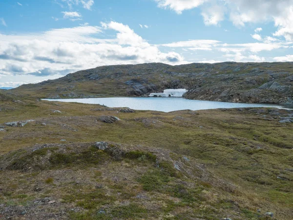 Krajobraz północny, tundra w szwedzkiej Laponii z błękitnym jeziorem arktycznym ze szmaragdami topniejącej jaskini śnieżnej, zielone wzgórza i góry na szlaku turystycznym Padjelantaleden. Letni dzień, błękitne niebo, białe chmury — Zdjęcie stockowe