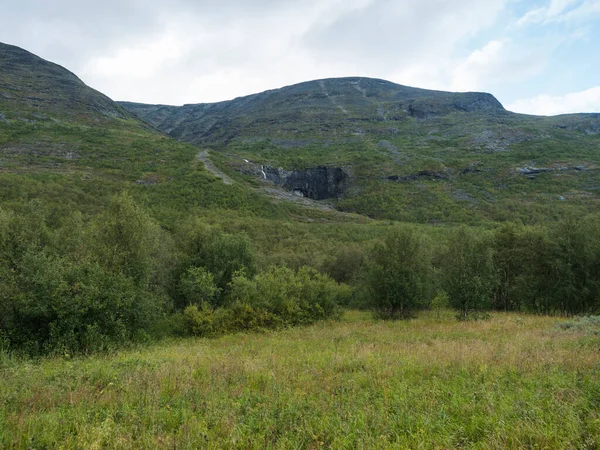 Beatiful északi táj, tundrán svéd Lappföld kis vízesés, zöld dombok és hegyek Padjelantaleden túraútvonal. Nyári borús nap — Stock Fotó