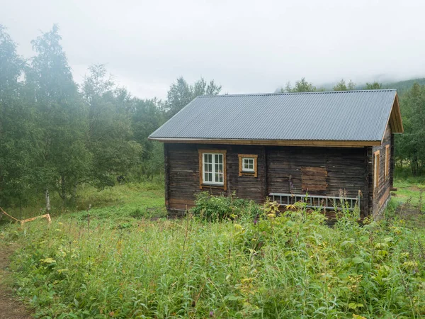 Uitzicht op STF Njunjes Bergcabine op een weide, humeurige regenachtige dag met dikke mist. Houten huisje ligt aan de oevers van de rivier de Tarra, aan de Padjelantaleden wandelweg. Lapland zomer landschap — Stockfoto