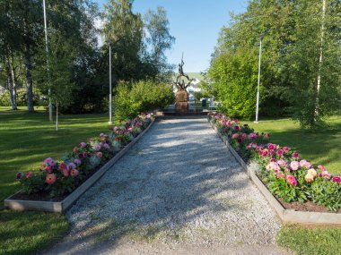 Jokkmokk, Norrbotten, Sweden, Agust 17, 2021: Flower decorations and statue at park in center of Jokkmokk, summer sunny day.