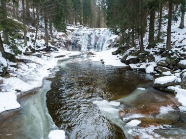 Mumlavsky vodopad, waterfall on Mumlava river stream in Krkonose National Park, Czech Republic in winter snow covered forest.