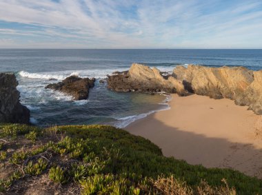 Porto Covo, Portekiz 'deki boş Praia dos Buizinhos kumsal manzarası. Okyanus dalgaları ve keskin kayalar. Altın saat