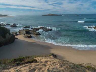 Portekiz 'in Porto Covo yakınlarındaki Rota Vicentina sahilinde okyanus dalgaları ve keskin kayalarla dolu boş Praia do Sissal kumsalı manzarası