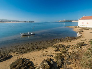 Mira Nehri 'nin ağzının küçük bir sahil evi ve demir atmış bir balıkçı teknesiyle Atlantik Okyanusu' na dökülüşü. Vila Nova de Milfontes, Vicentine Sahili Doğal Parkı Portekiz.