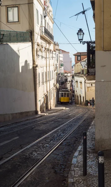 ポルトガルのリスボン 2021年10月24日 ポルトガルの首都アルファマの典型的な黄色のヴィンテージトラム番号28行 アイコンとシンボルを持つ急な狭いリスボンの通りの景色 — ストック写真