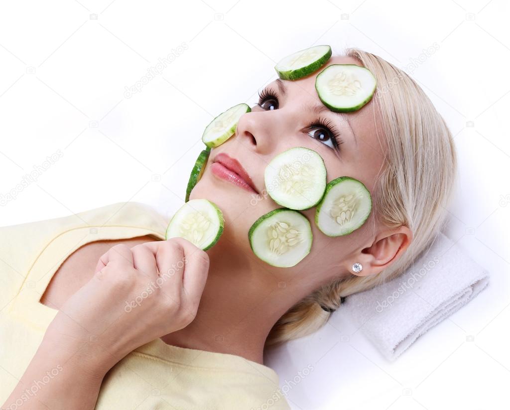 Young girl applying facial cucumber mask