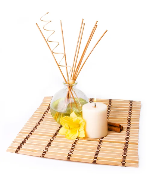 Ambiente de spa com varas de aroma, vela, flor amarela e canela em esteira de bambu isolado em branco — Fotografia de Stock