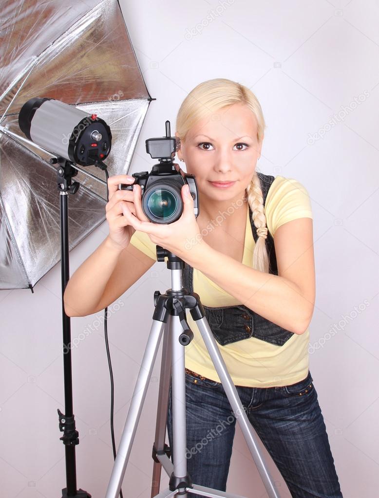 Professional photographer, young beautiful girl with the camera in photo studio