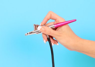 mavi arka plan üzerinde elinde airbrush