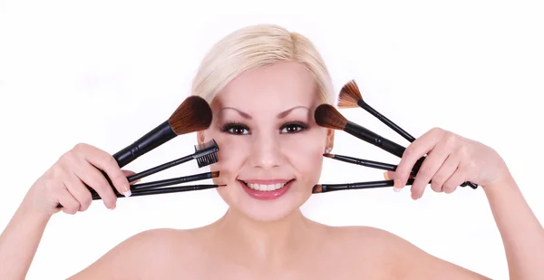 Schöne lächelnde blonde junge Frau mit Make-up-Pinseln isoliert auf weiß — Stockfoto
