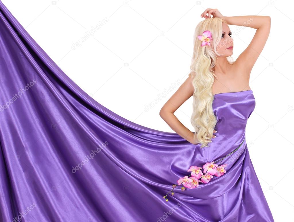 Sexy blonde young woman in purple silk dress with orchid flowers isolated on white