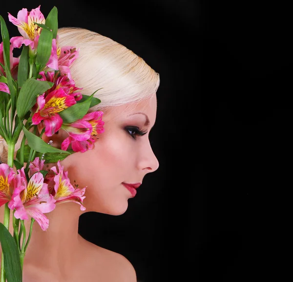 Beautiful blonde young woman with pink irises flowers over black background, fashion model — Stock Photo, Image