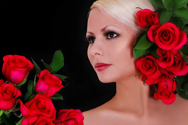 Bella bionda giovane donna con rose rosse su sfondo nero, ritratto di moda — Foto Stock