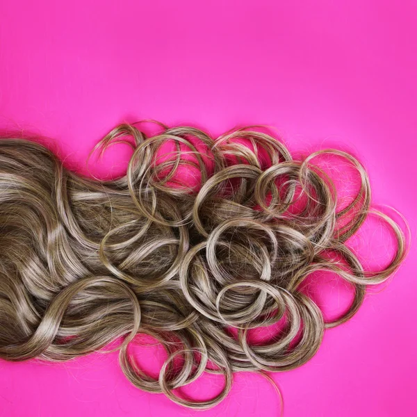 Capelli castani ricci su sfondo rosa — Foto Stock