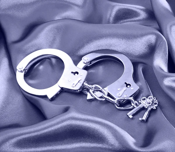 Handcuffs and keys on silk fabric — Stock Photo, Image