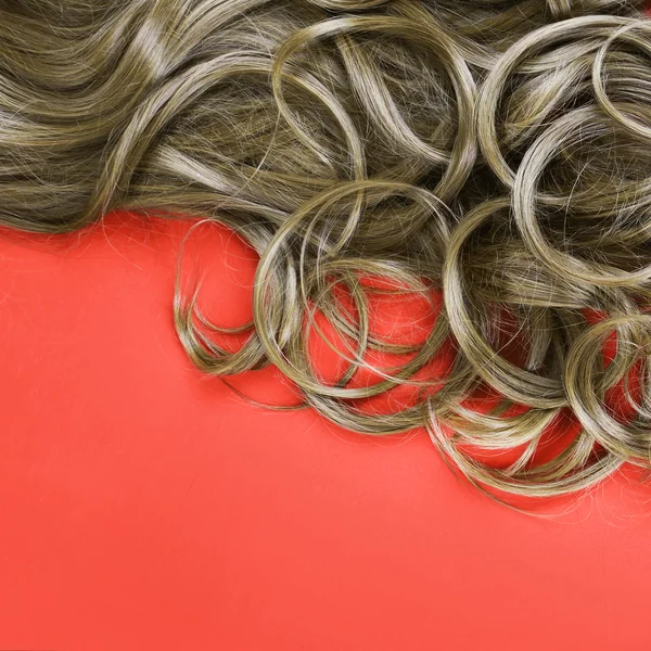 Pelo castaño rizado sobre fondo rojo, primer plano —  Fotos de Stock