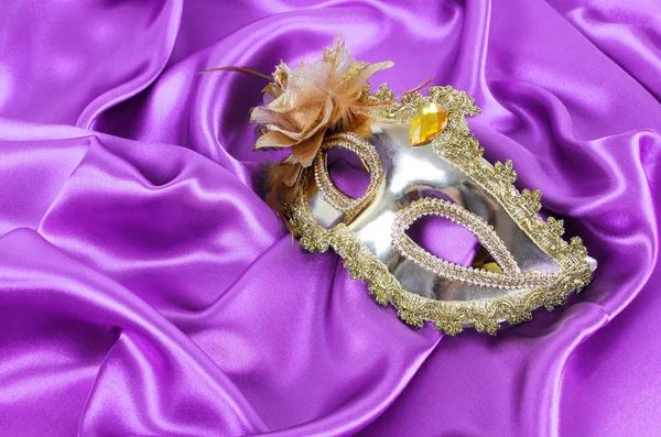 Goldene Karnevalsmaske auf lila Seidenstoff — Stockfoto