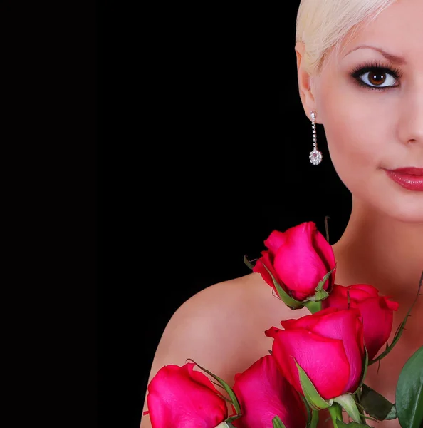 Красивая молодая женщина с красными розами на черном фоне с копировальным пространством, модный портрет — стоковое фото