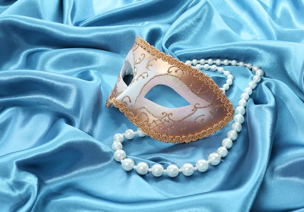 Glitter goud masker en parel ketting op turquoise zijde draperen achtergrond — Stockfoto