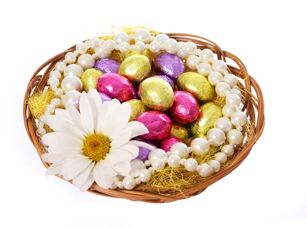 Uova di Pasqua, colorate uova di cioccolato con fiore di camomilla e collane di perle in cestino isolato su sfondo bianco — Foto Stock