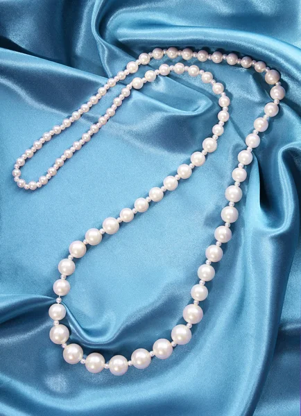 Pearl necklace on turquoise silk fabric, luxury — Stock Photo, Image