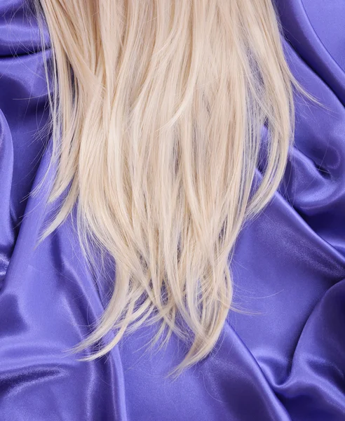 Blonde straight hair on blue silk fabric, hair care — Stock Photo, Image