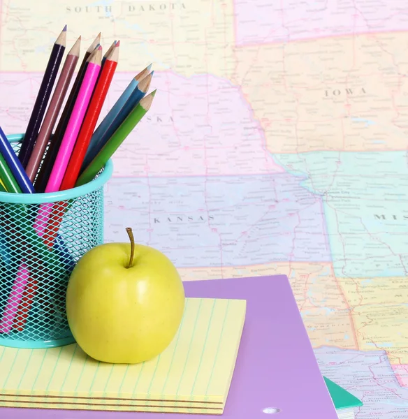 Torniamo al concetto di scuola. Una mela e matite colorate su mucchio di libri sulla mappa — Foto Stock