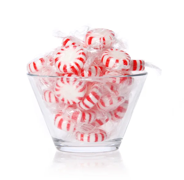 Bonbons à la menthe poivrée dans un bol en verre isolé sur blanc. Bonbons de Noël à la menthe rayée rouge, macro — Photo