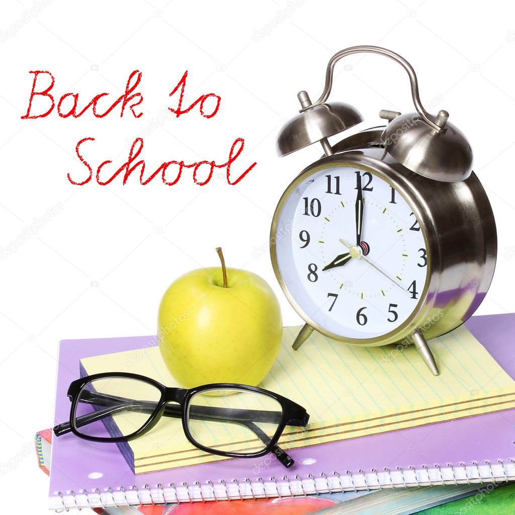 Back to school concept. An apple, alarm clock and glasses on pile of books isolated on white background