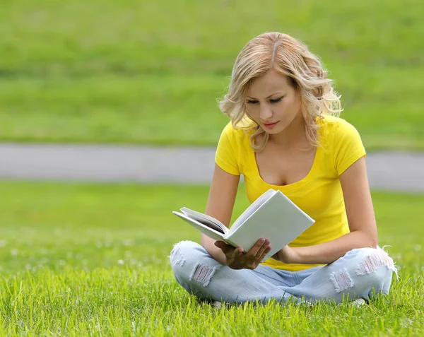 Ragazza che legge il libro. Bionda bella giovane donna con libro seduto sull'erba. All'aperto. Giornata di sole. Ritorno a scuola — Foto Stock