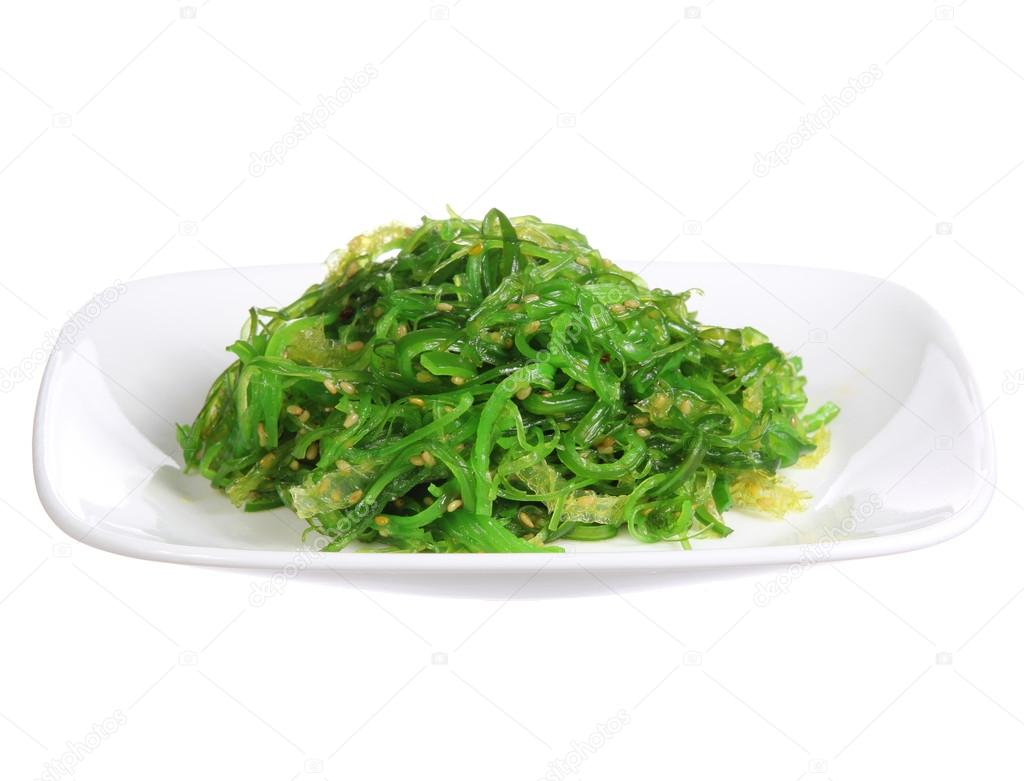 Chuka salad. Seaweed with sesame seeds on ceramic plate isolated on white background. Japanese Cuisine