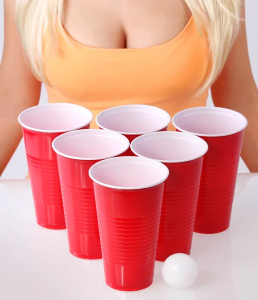 Beer pong. czerwone kubki plastikowe z ping pong piłkę i blondynka dziewczyny w seksowny top zbiornika. zbliżenie — Zdjęcie stockowe