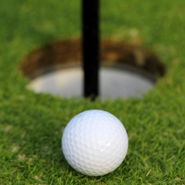 Yeşil çimenlerin üzerinde fincan içine düşmek için golf topu. portre