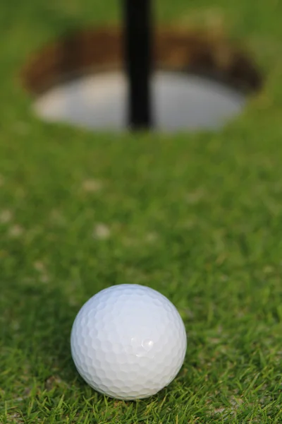 Pelota de golf a punto de caer en la copa, sobre hierba verde. Primer plano. —  Fotos de Stock