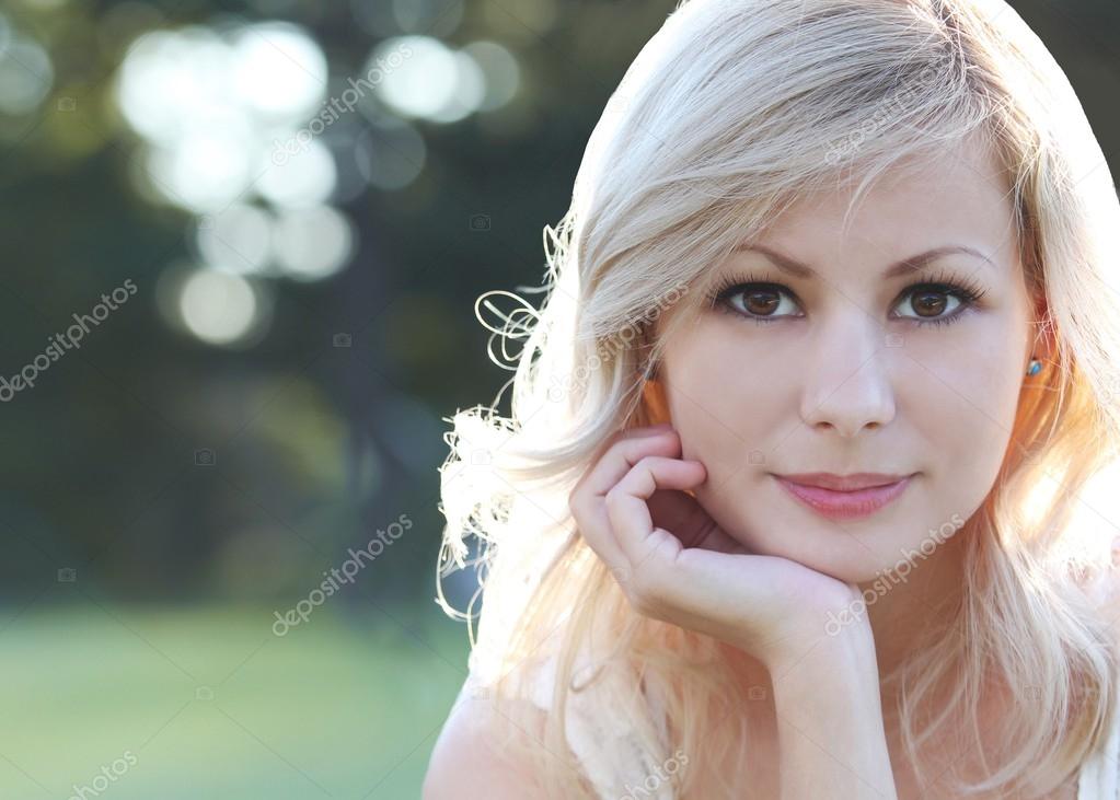 Smiling blonde girl. Portrait of happy beautiful young woman, outdoors. Copy space. Bokeh