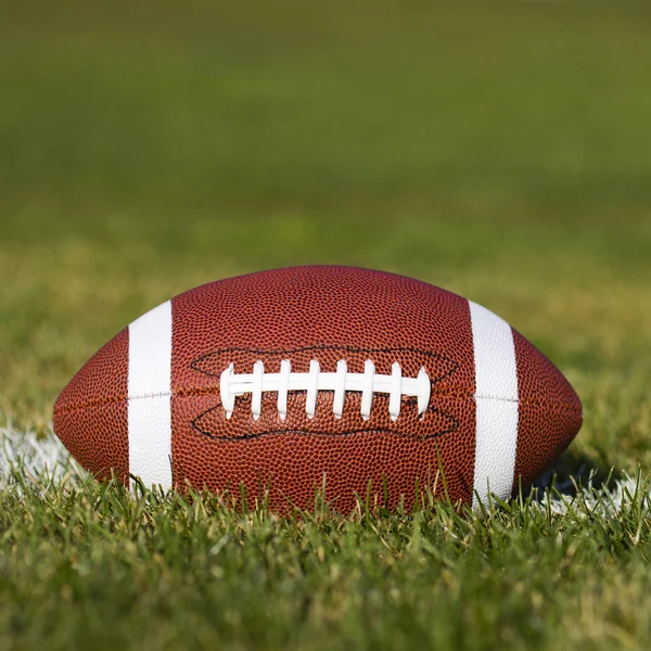Amerikansk fotboll på fältet med yards linjen och grönt gräs. — Stockfoto