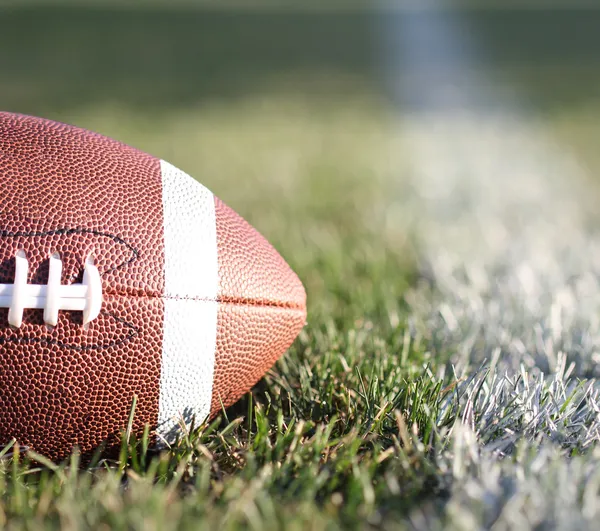 Football américain sur le terrain avec ligne de cour et herbe verte — Photo