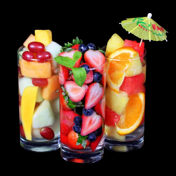 Fruit cocktails op zwarte achtergrond. verse plakjes van verschillende vruchten in glas met munt en een paraplu op de top. gezonde drank — Stockfoto